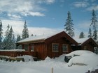 Se på fasade av Tors stavlaft hytte i vinter